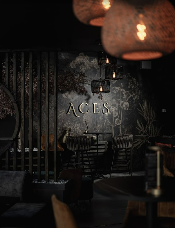 ACES signage on botanical wall with rattan pendants